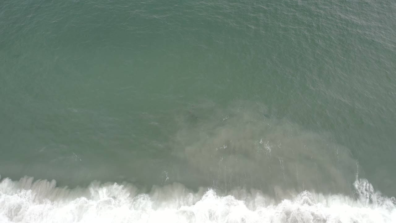 Overhead view of grayish blue water in Los Cabos, Mexico, with a bright white foam line along the lower edge and no visible people.