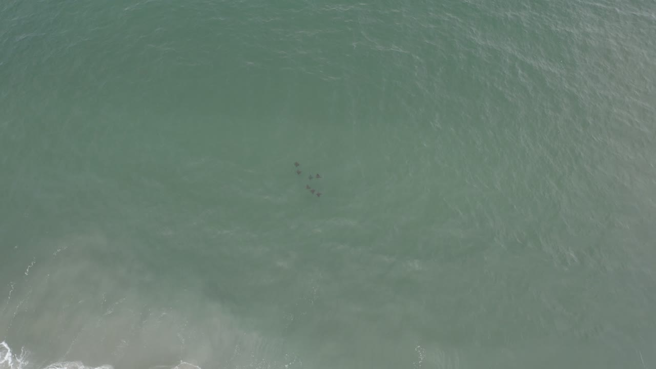 Overhead view of green-blue ocean water in Los Cabos, Mexico, with a pale foam patch near the lower edge and no visible people.
