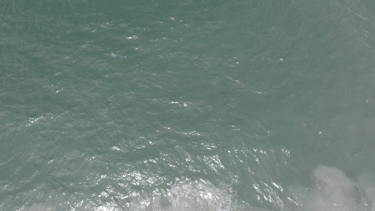 Overhead view of blue-green ocean water in Los Cabos, Mexico, with sunlit ripples and faint pale patches below the surface, no visible people.