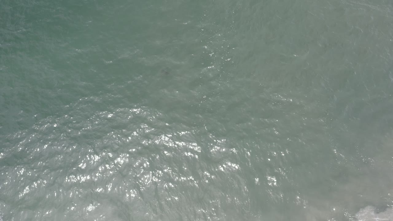 Top-down ocean waves with a brighter patch of broken water near the right side.