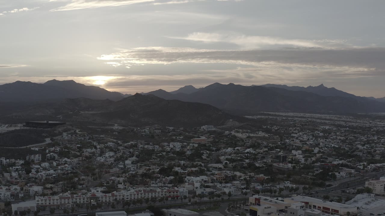 Backlit mountains behind a town at evening
