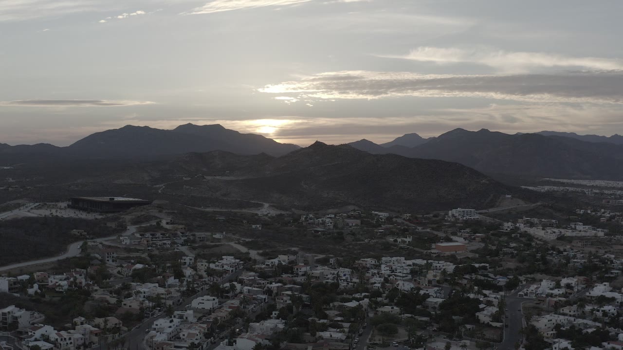 Dusk view over houses, hills, and dark mountains.
