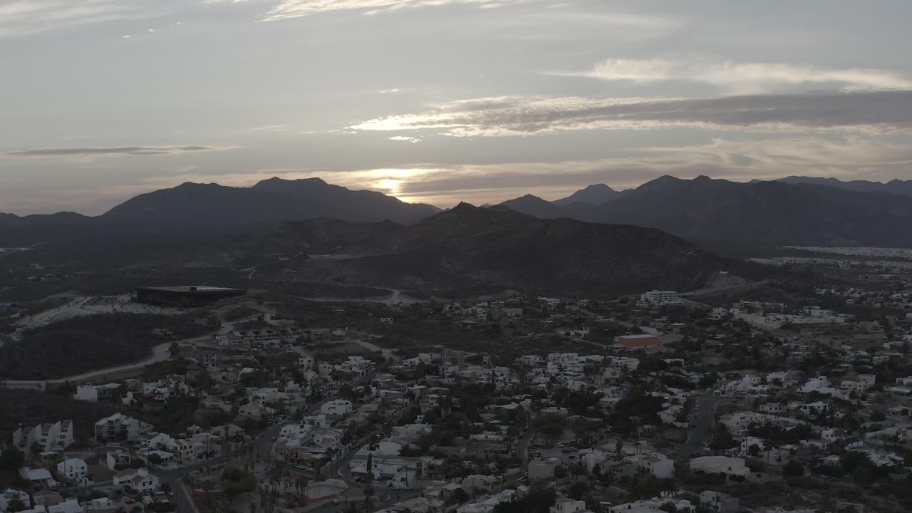 Cloud-filtered dawn light over hills, mountains, and town