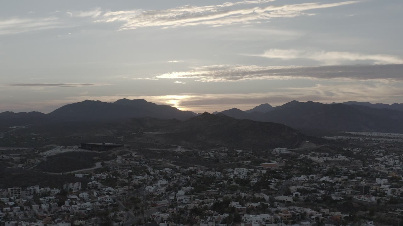Sunset behind mountains over a dark city view