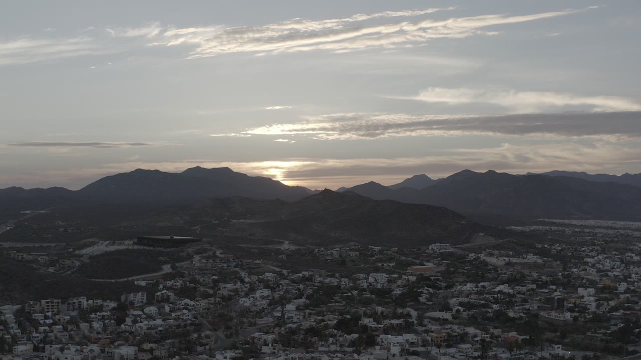 Dawn light behind mountains above a dark town