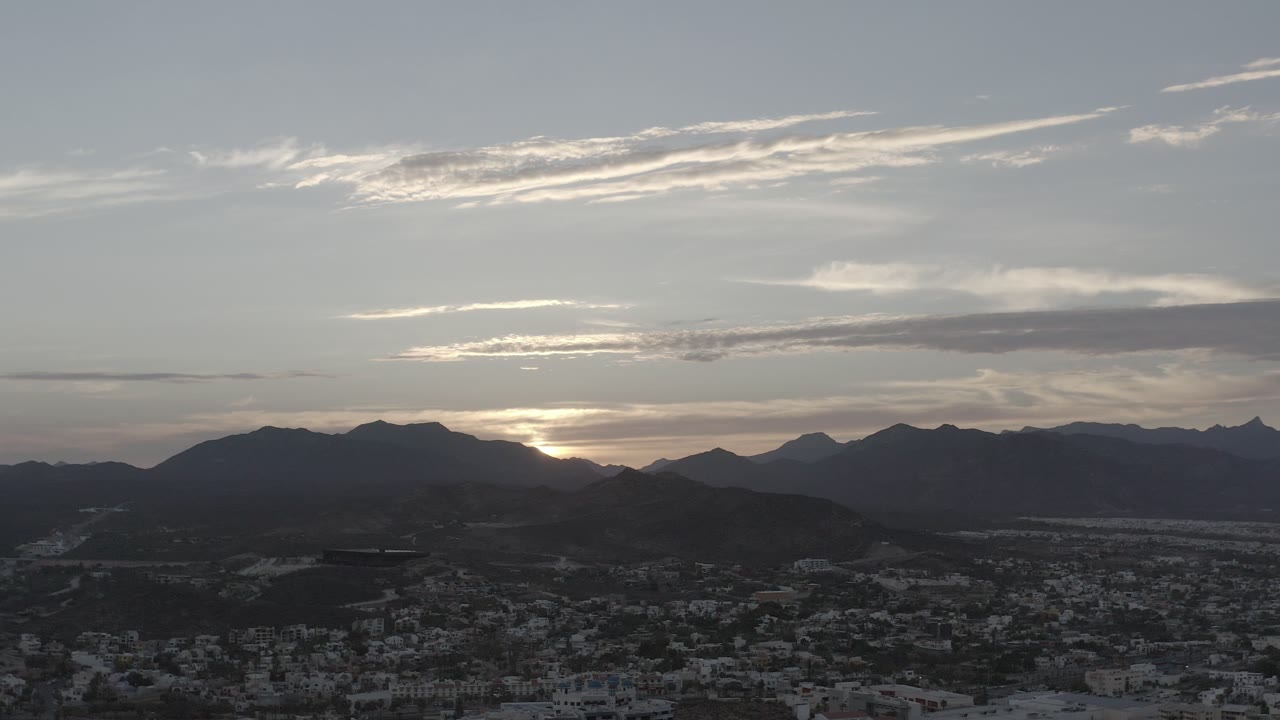 Cloudy sunset sky over silhouetted mountains and town