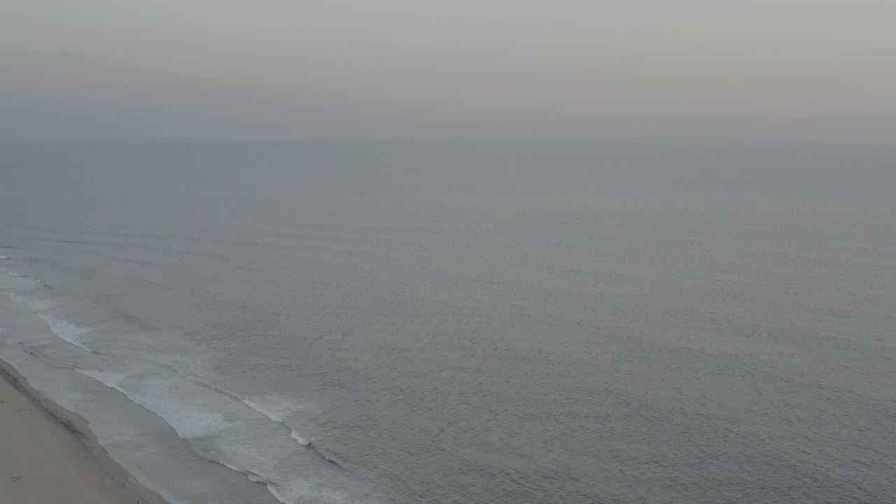 Foggy ocean horizon with surf reaching a sandy beach