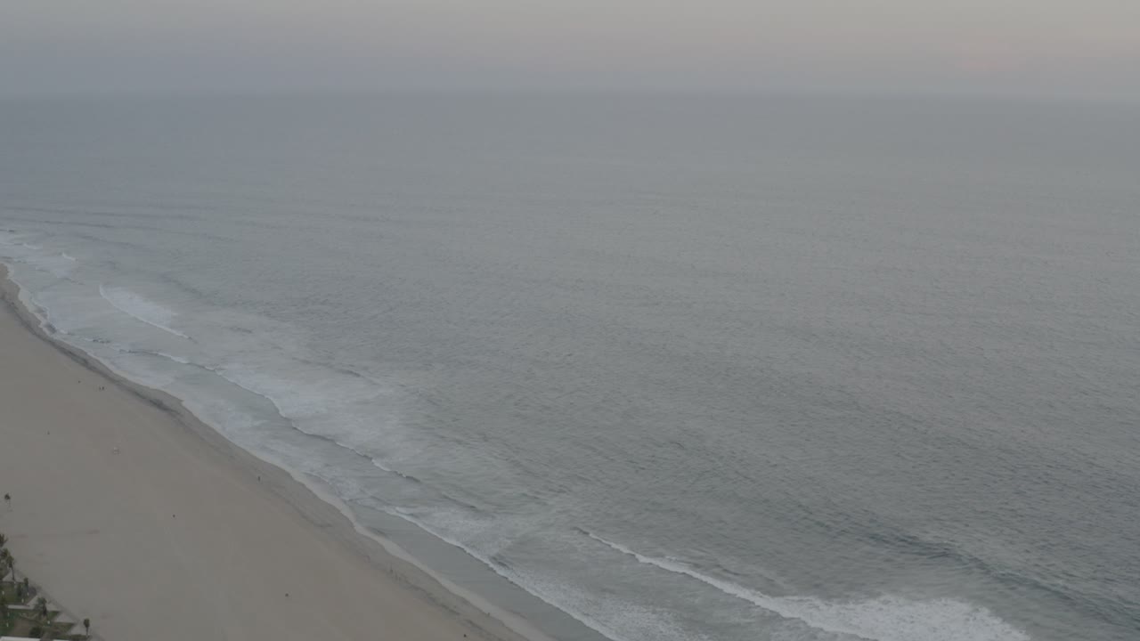 High aerial view of gray ocean waves reaching a sandy beach