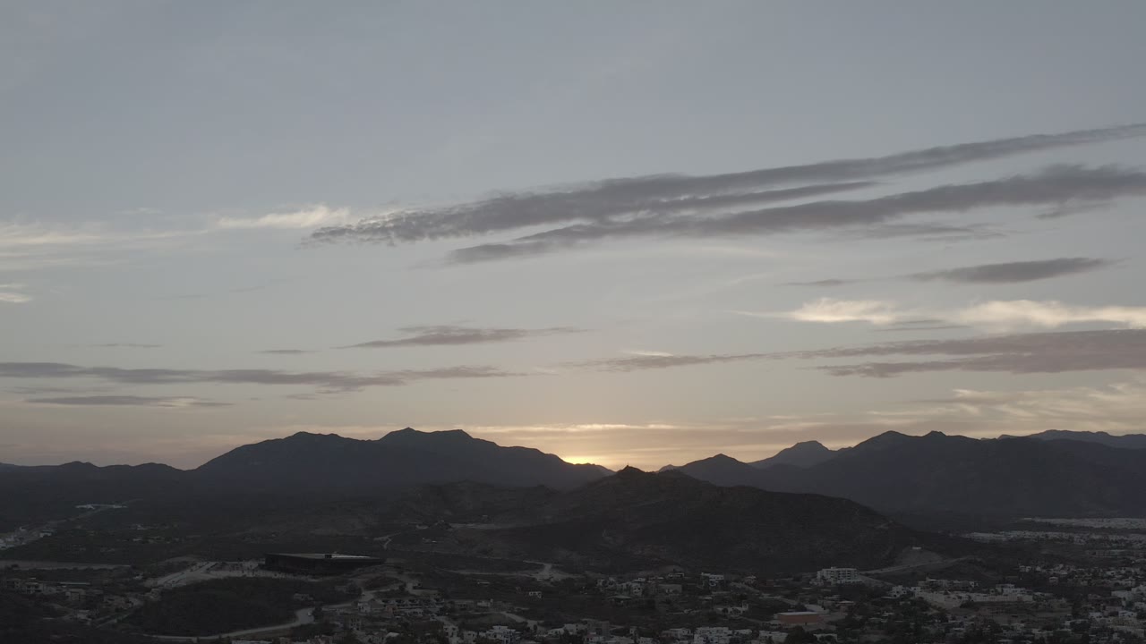 Los Cabos mountain ridges sit in silhouette as a faint warm sunset band shows behind the peaks, with no visible people in the frame.