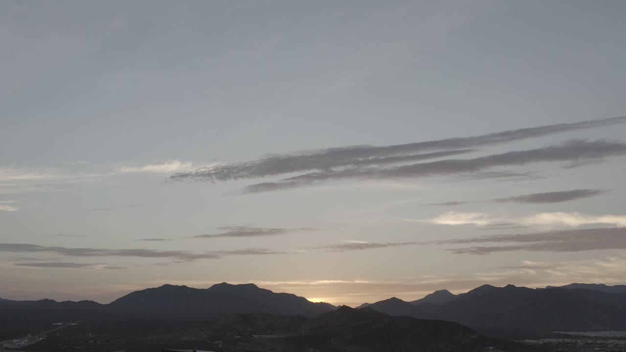 Distant mountains and city under a gray sunset sky.