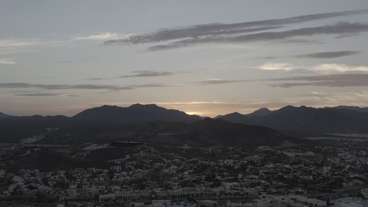 Dusk view of mountains above a low cityscape.