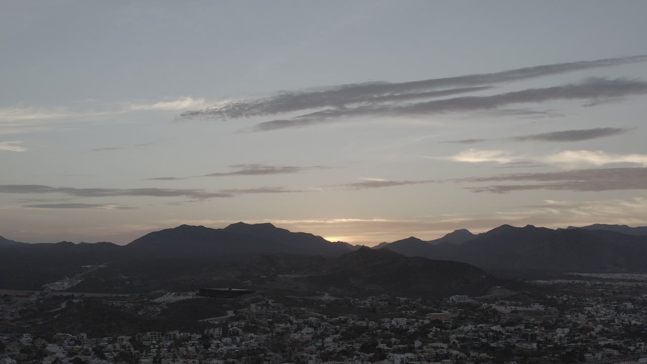 Dusk sky over dark mountains and a distant town.