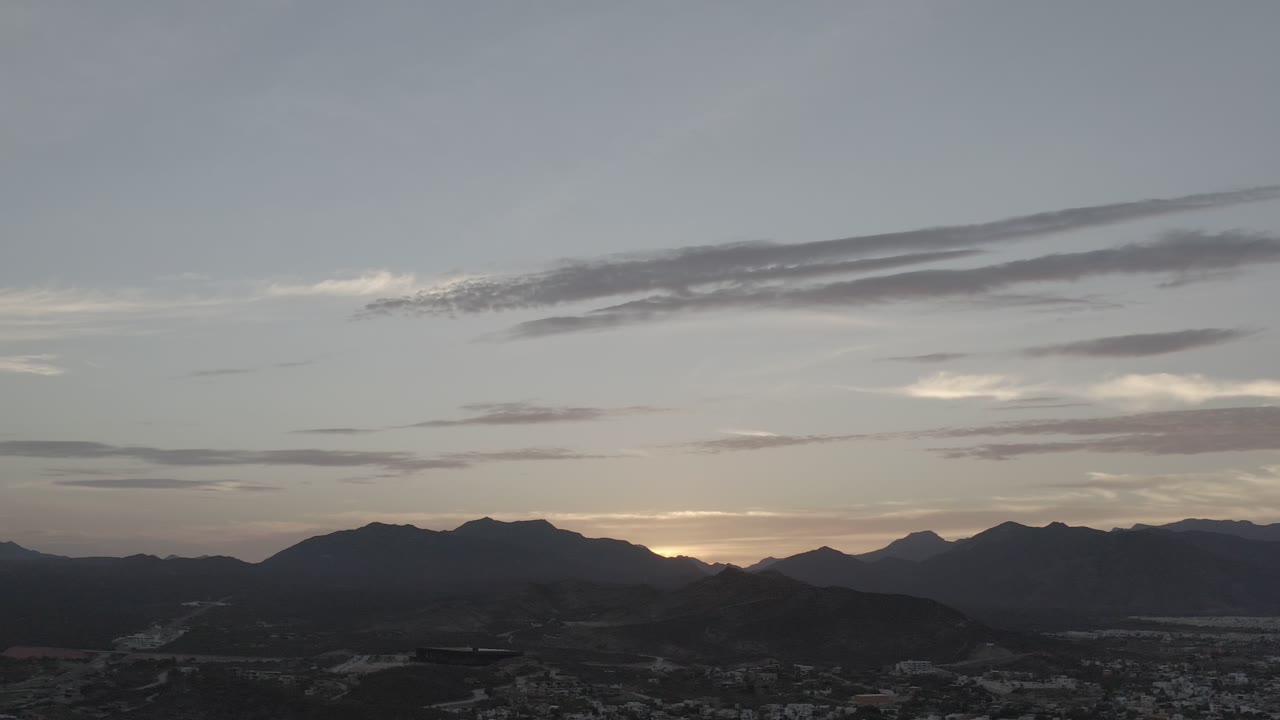 Los Cabos, Mexico mountain ridge at dusk with a low warm horizon, broad blue-gray sky, and no visible people.