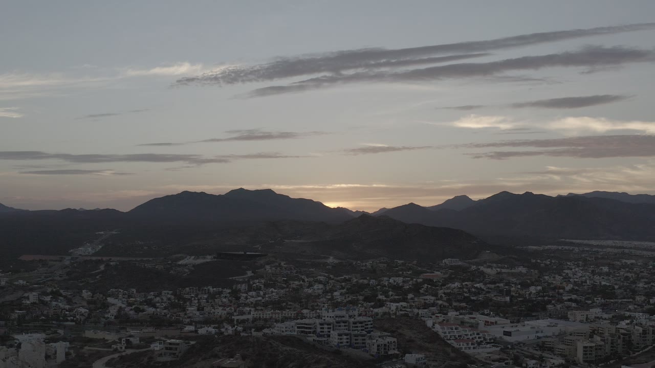 Dawn sky over a dark town and mountain ridge.