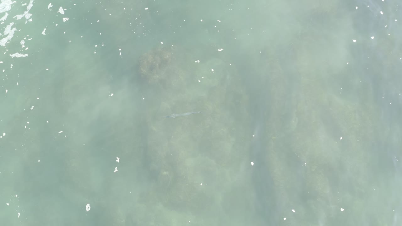 Aquamarine water with white foam over submerged rocks.