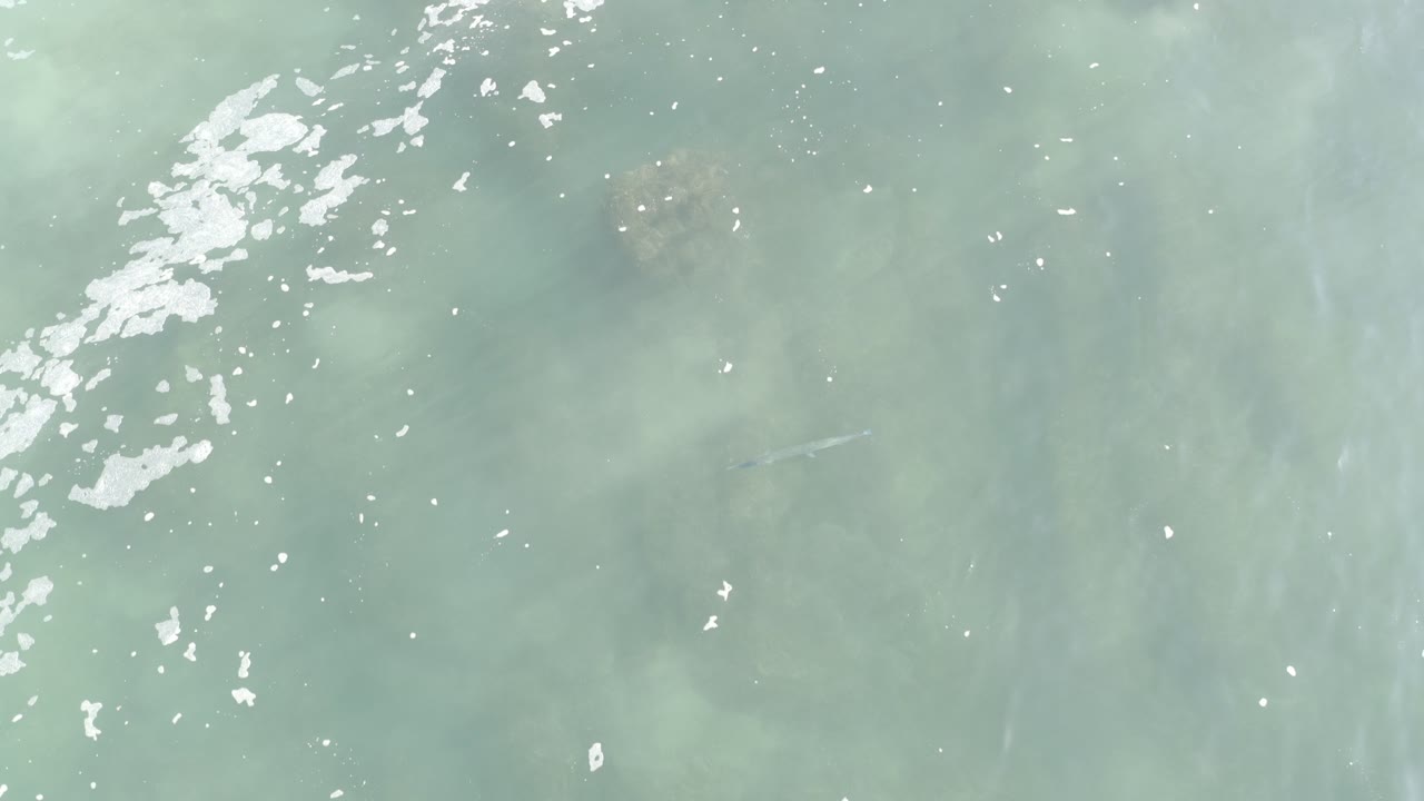 Pale aquamarine water with white foam and submerged rocks.