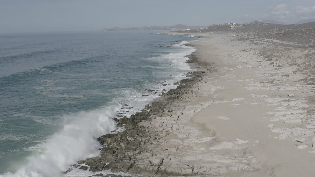 Large white wave breaks against the rocky shore.