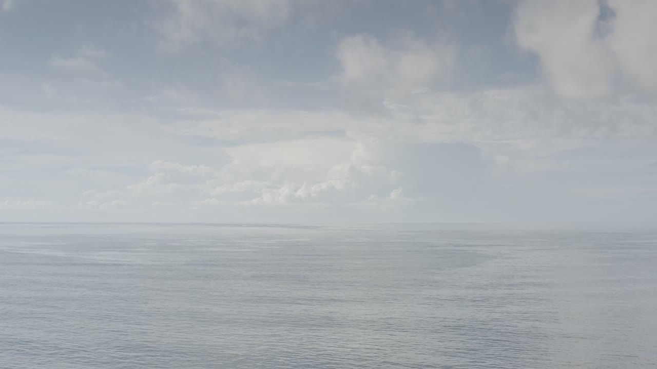 Muted ocean horizon under broad gray clouds.