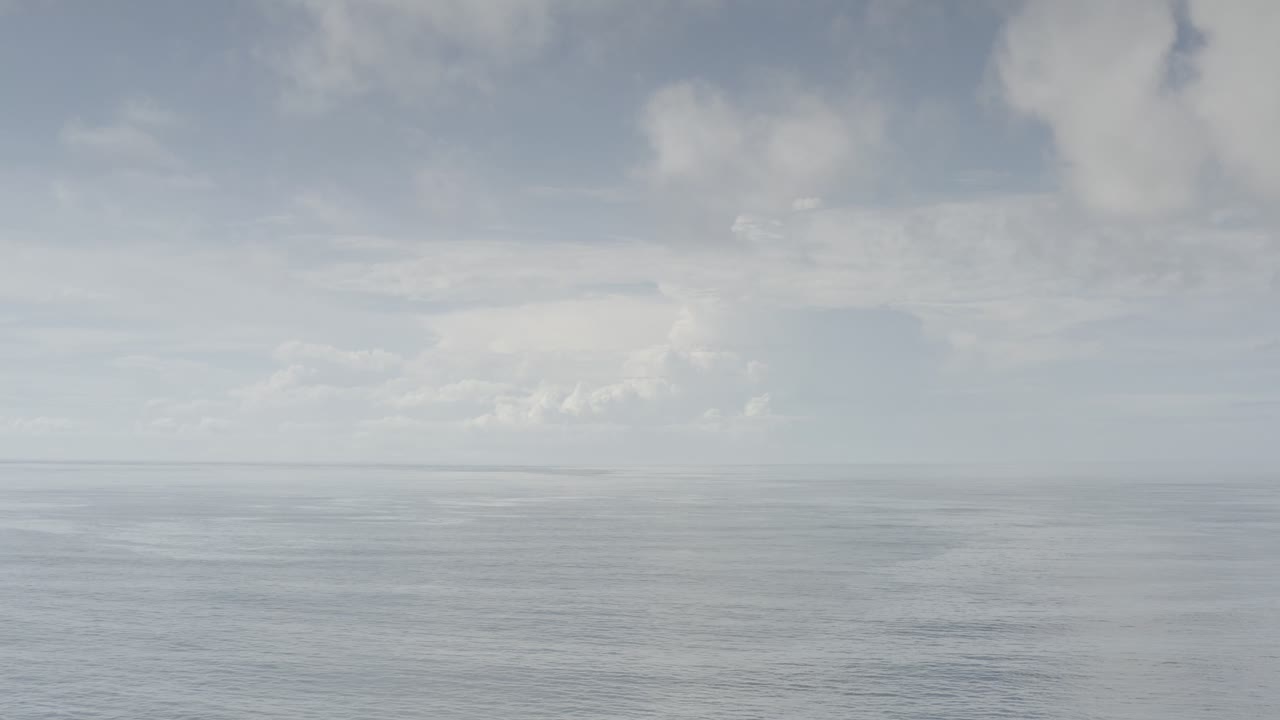 At 0:01, the Los Cabos, Mexico frame holds a wide ocean view under bright white cloud cover and hazy blue sky with no visible people.