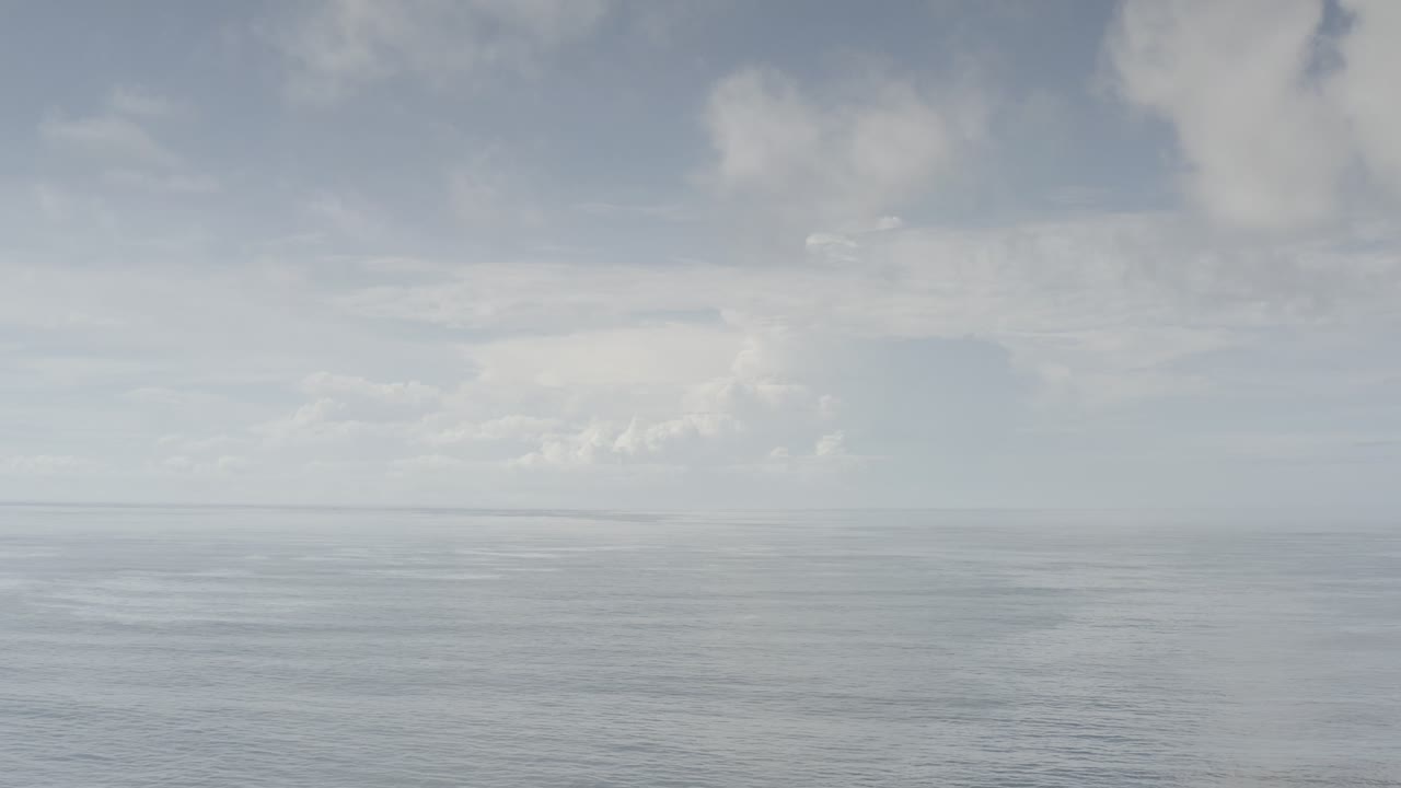 A Los Cabos, Mexico sky-and-sea frame with a level horizon, diffuse cloud cover, muted blue-gray water, and no visible people.