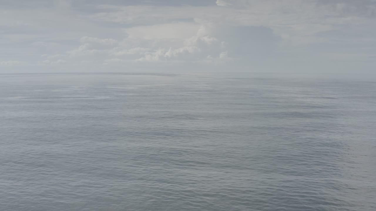 Muted ocean with a foggy sky and faint land on the left.