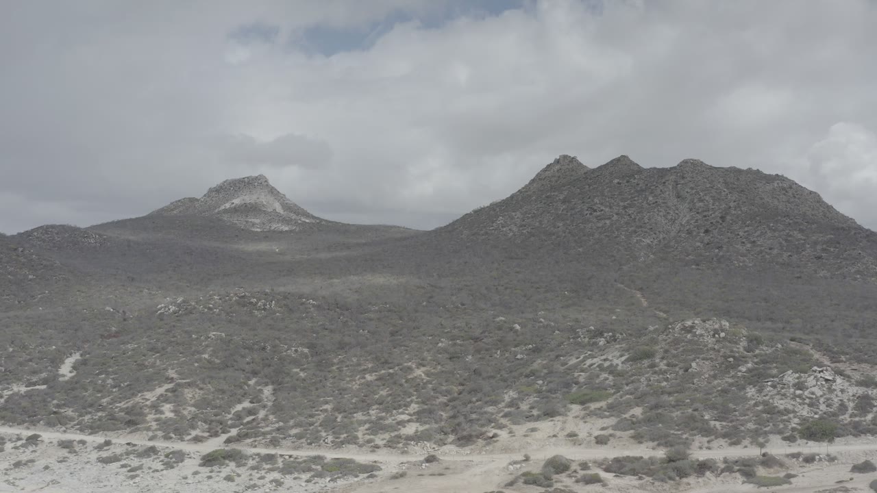Dark rocky hills and desert scrub beneath cloud cover.