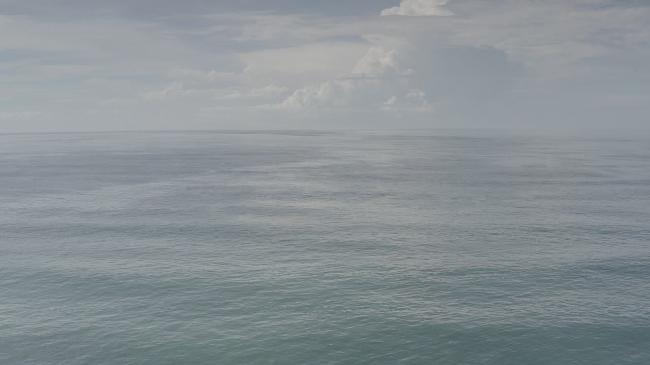 Open sea under a cloudy sky with a flat horizon.