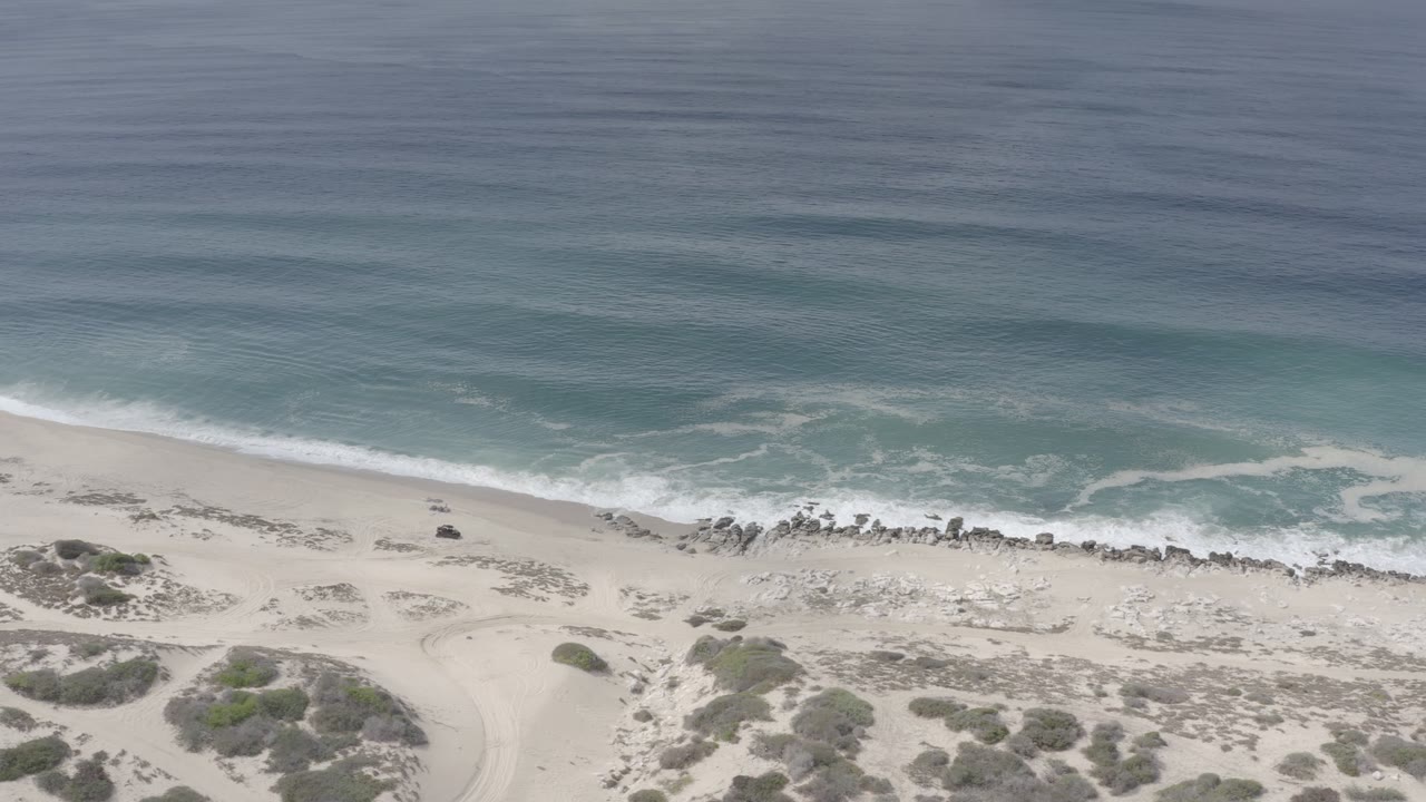 Blue ocean and foam line above an empty sandy shore