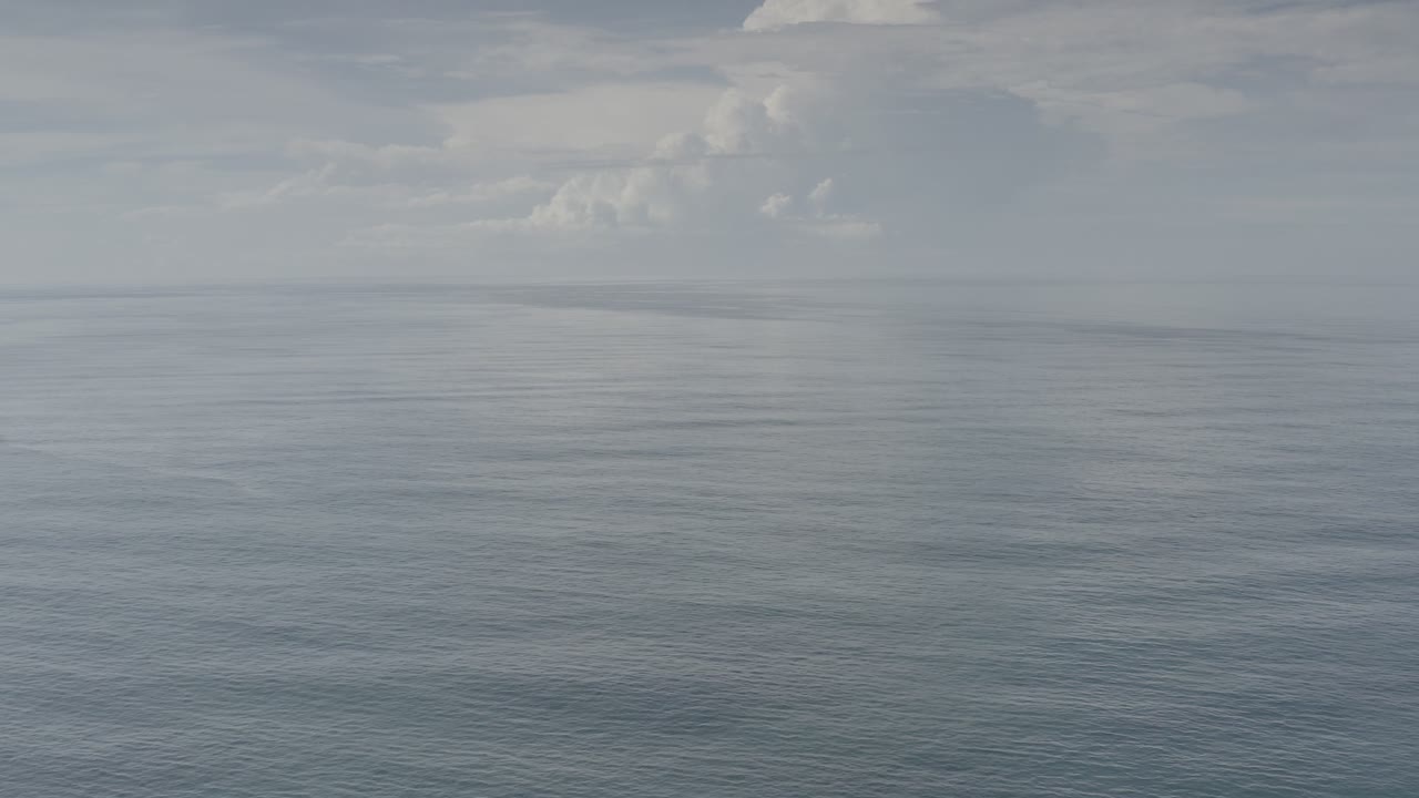 Calm sea under a muted sky with distant clouds