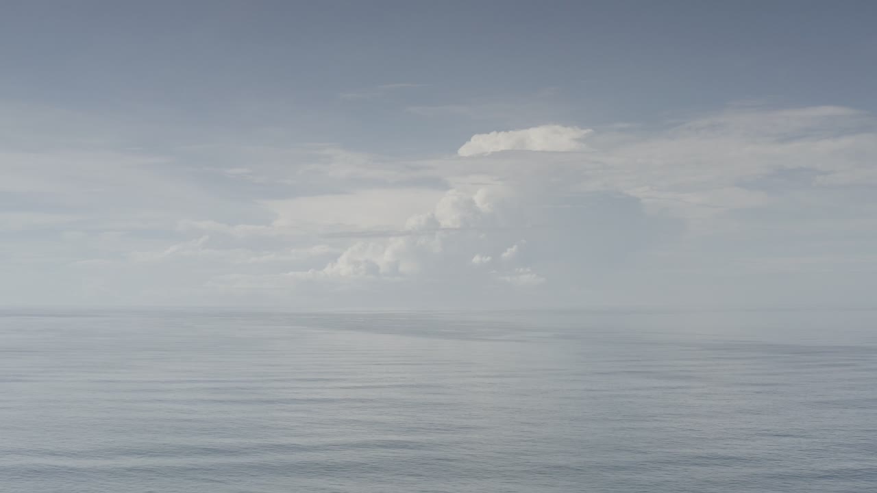 Large white clouds over a calm sea horizon