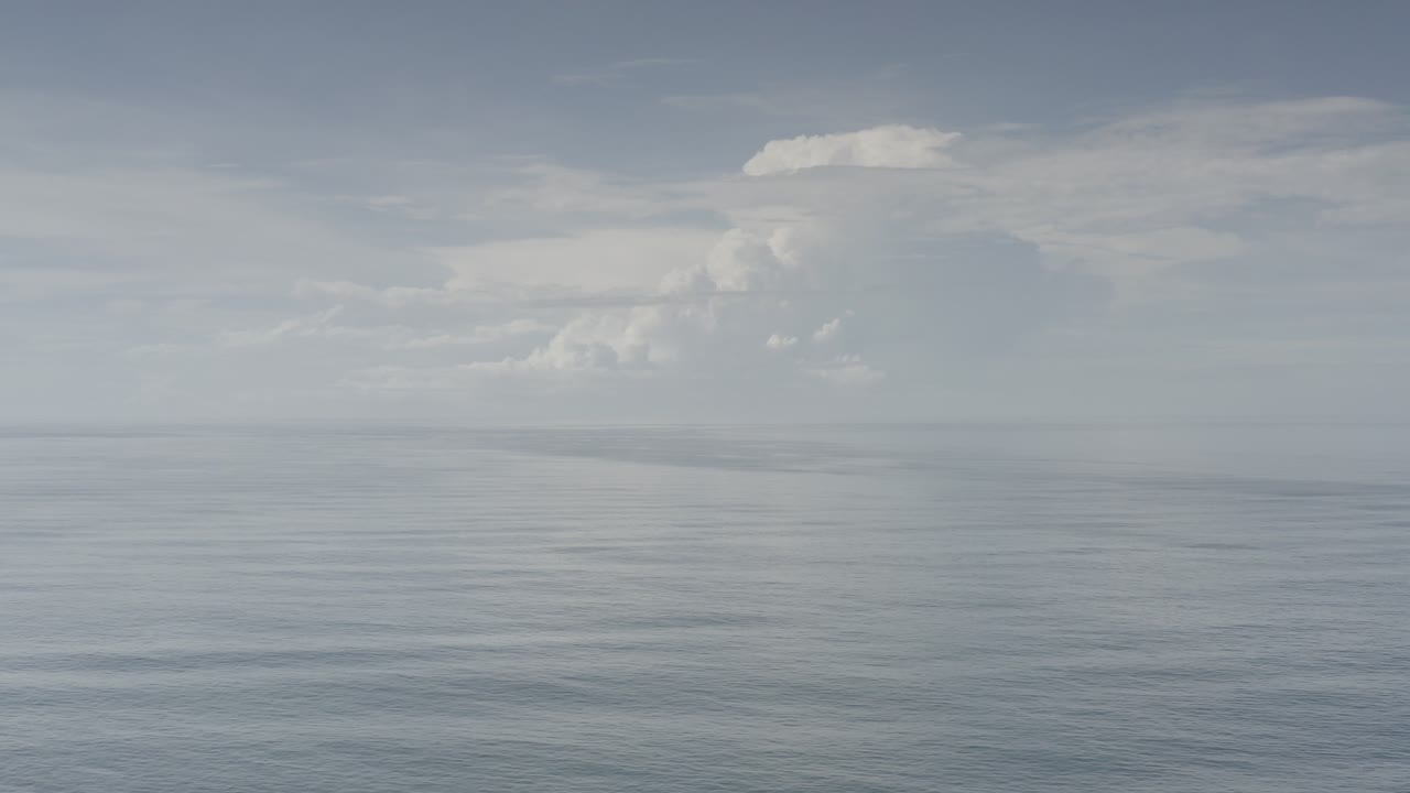 Wide view of the Los Cabos ocean with gray-blue water, a level horizon, soft cloud layers, and no visible people.