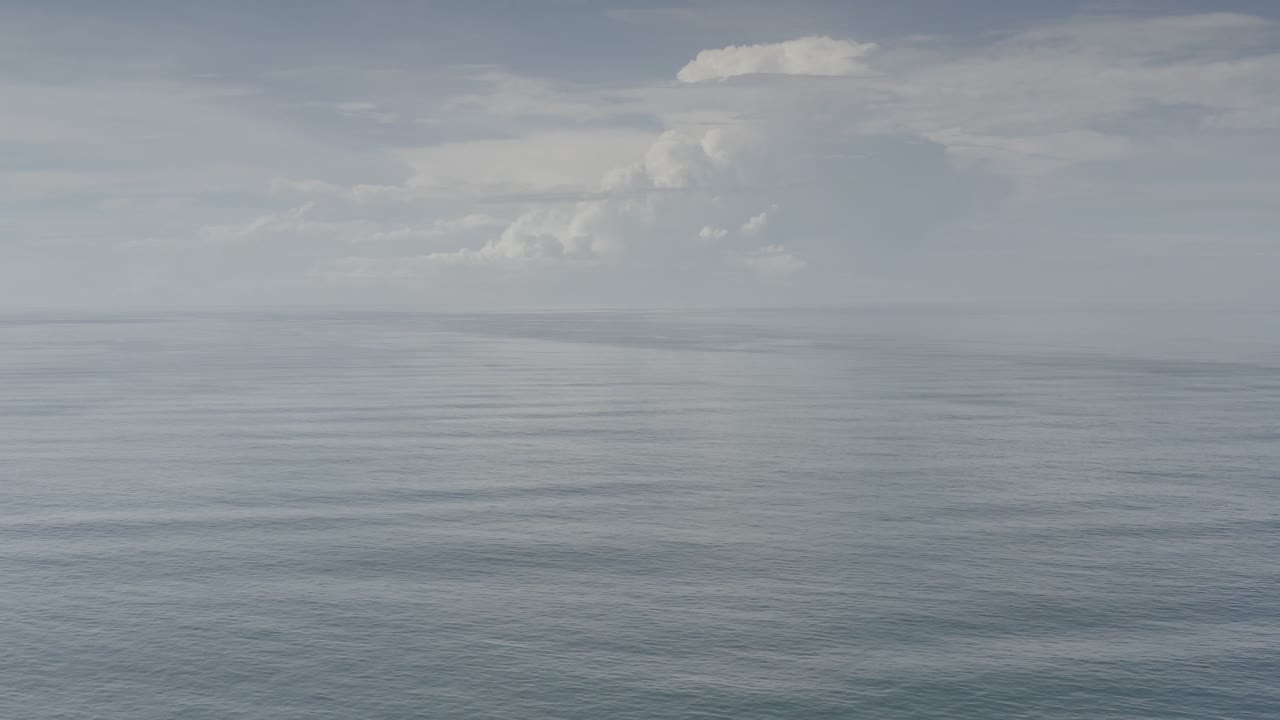Los Cabos ocean water stretches toward a distant horizon with muted cloud shapes above and no visible people in frame.