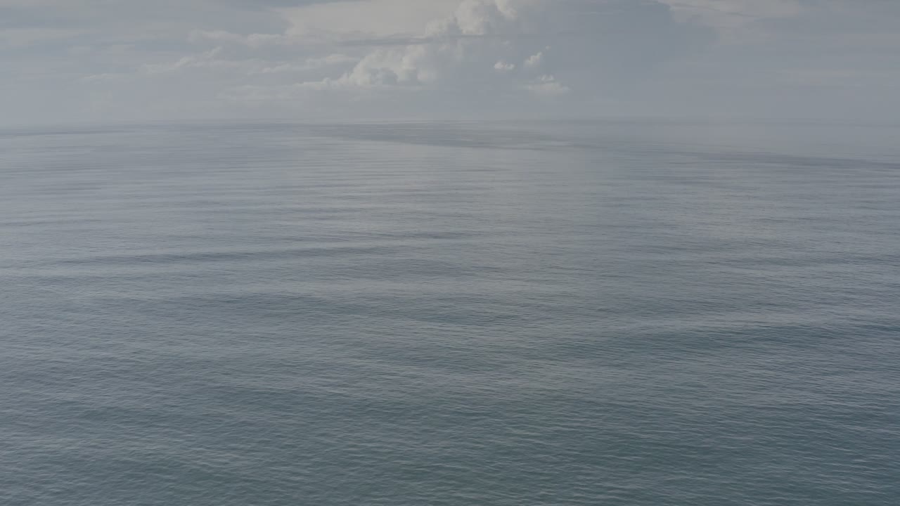 Opening frame of Los Cabos ocean water under gray cloud cover, with a distant horizon and no visible people.
