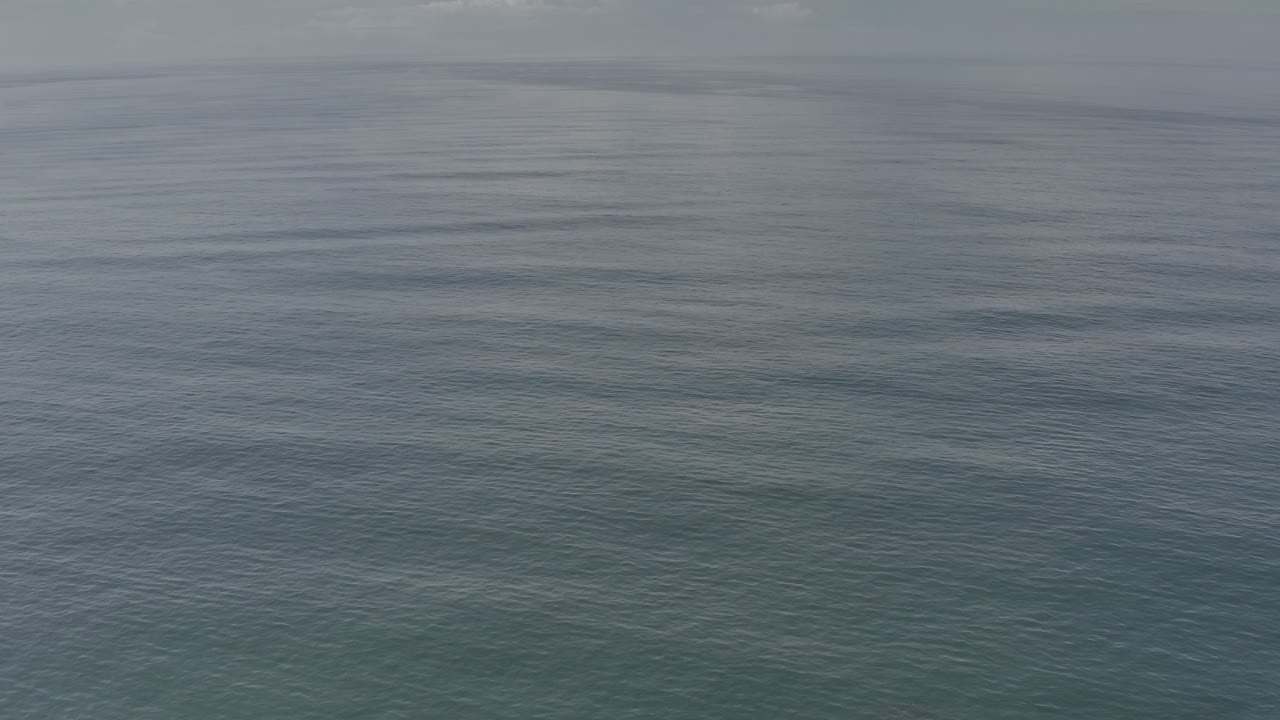 A wide view of Los Cabos ocean water shows fine surface ripples, subdued gray-blue tones, and no visible people.