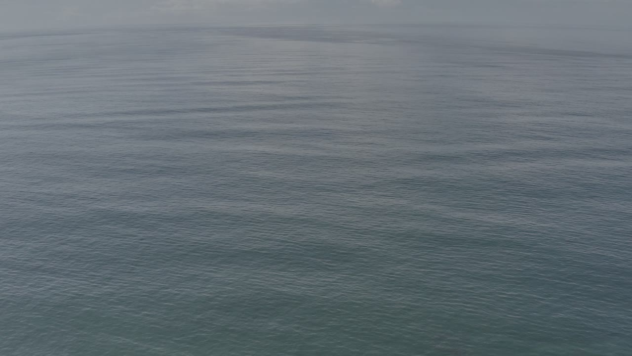 Calm ocean surface with darker bands of water near the horizon.