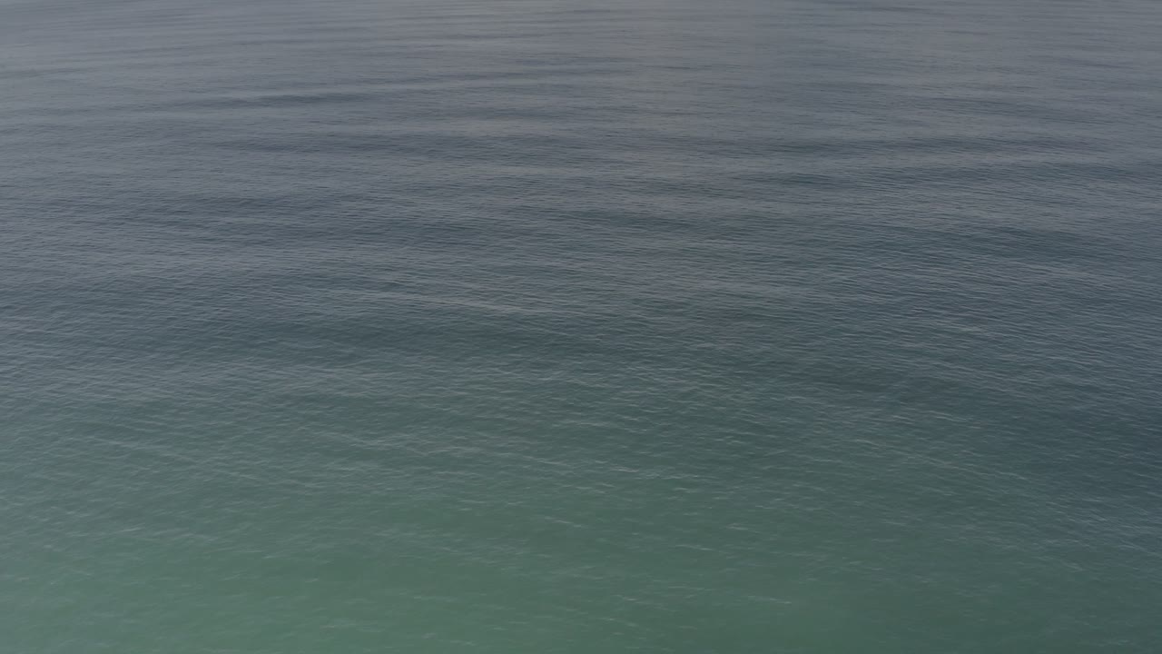 Close water texture with muted green-blue sea and darker ripples.