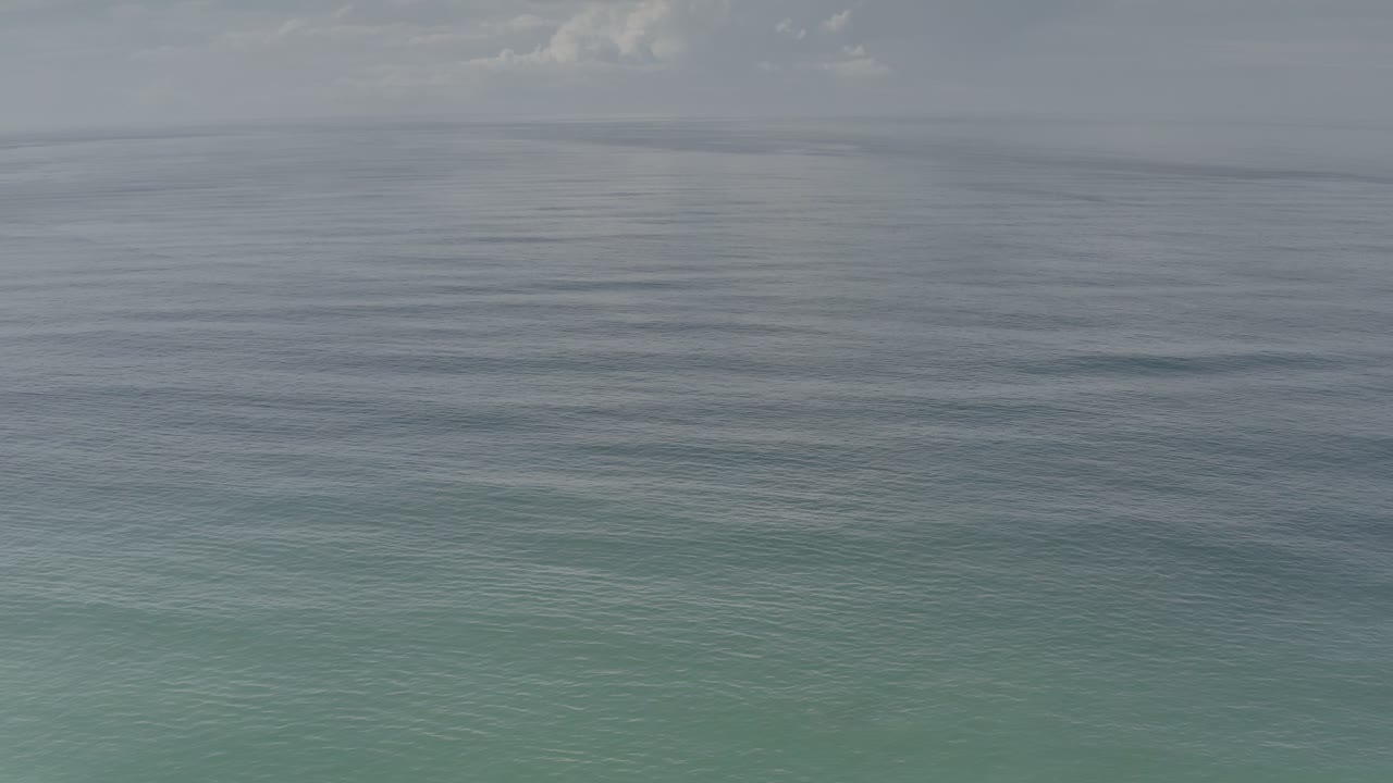 Los Cabos ocean water fills the frame at 0:01, with a smooth gray horizon band, pale clouds above, and no visible people or boats.