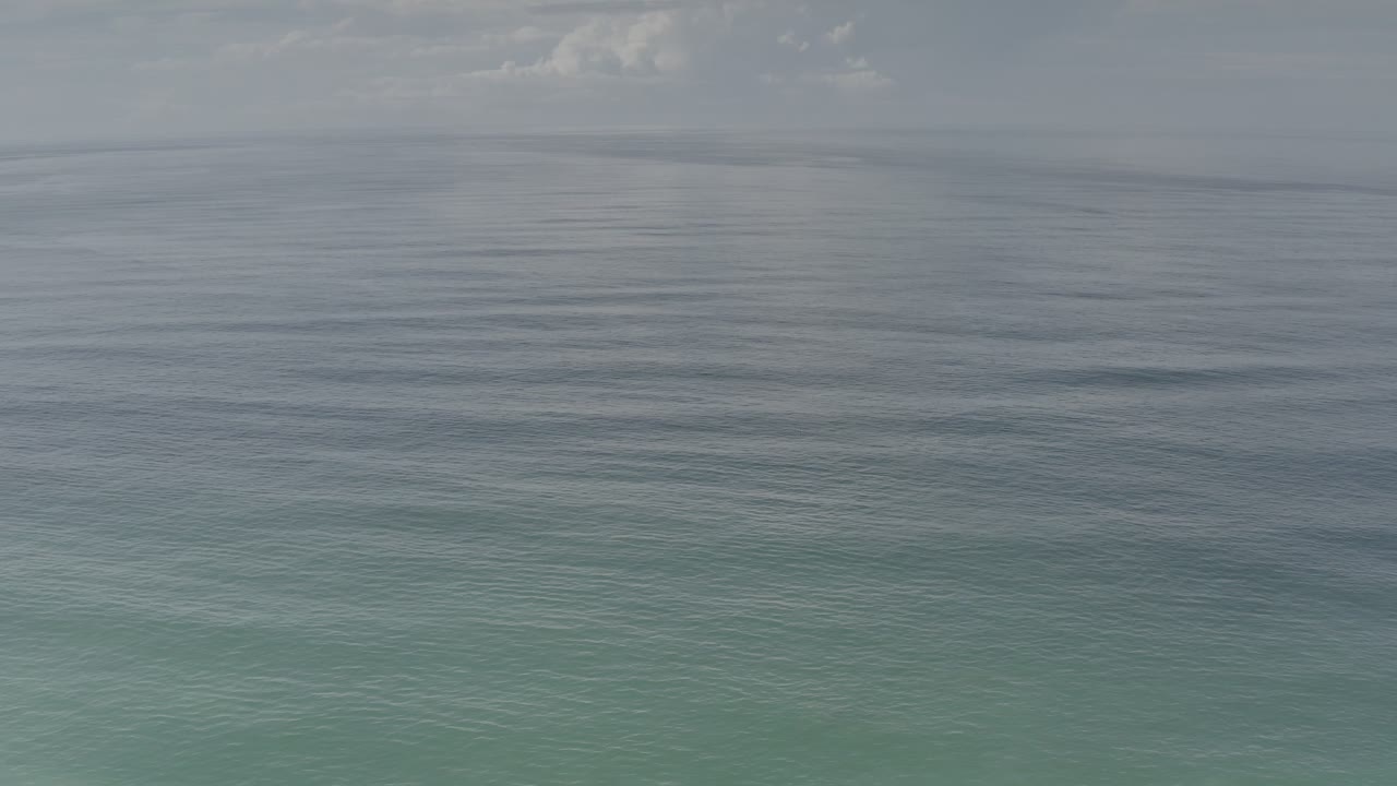 Open water with small waves below a cloudy gray-blue sky.
