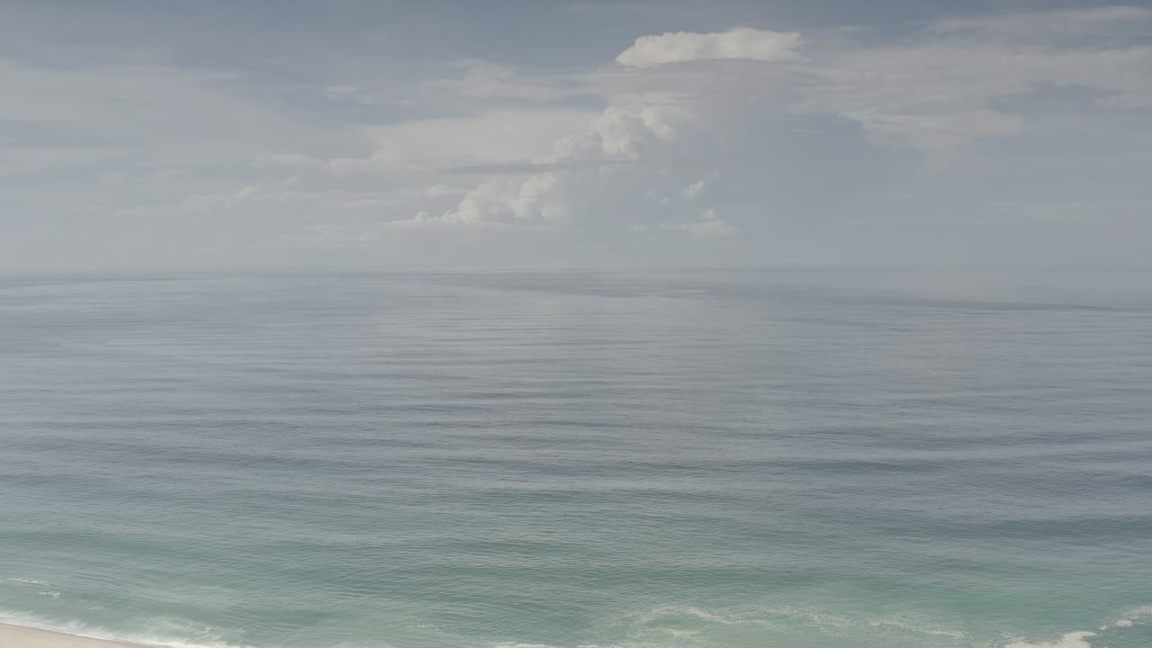 Los Cabos ocean surface under muted daylight, with the horizon high in frame, cloud banks above the water, and no visible people.