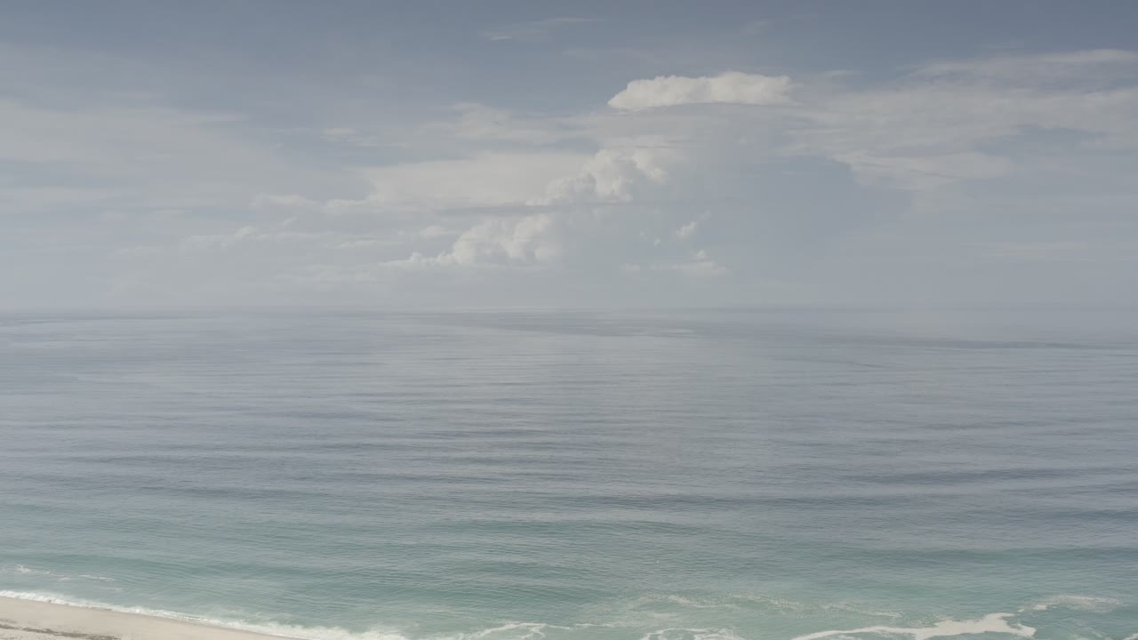Pale ocean horizon with clouds and a thin beach edge