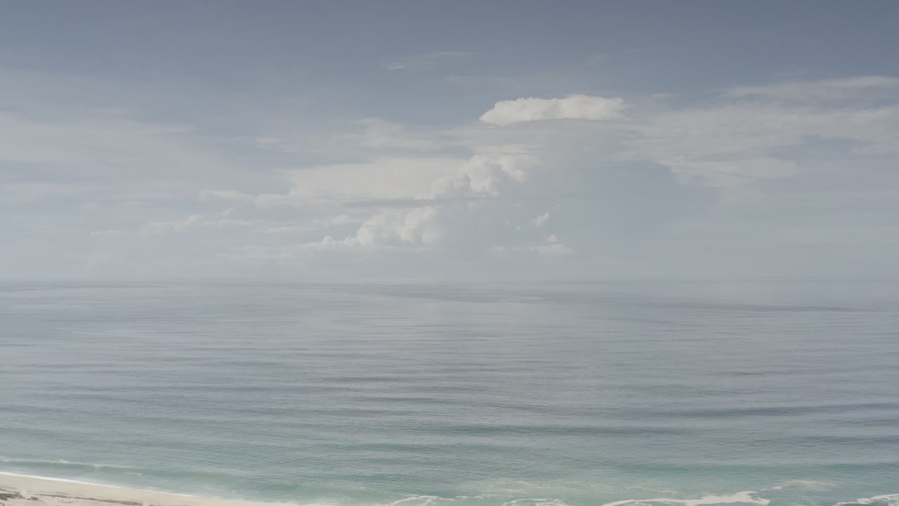 Los Cabos ocean horizon with a large cloud mass left of center, muted blue-gray water, and no visible people.