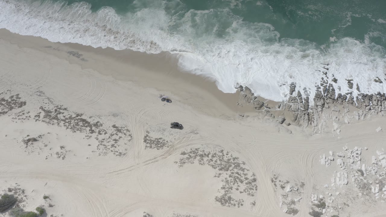 Top-down shoreline with surf foam and sandy beach