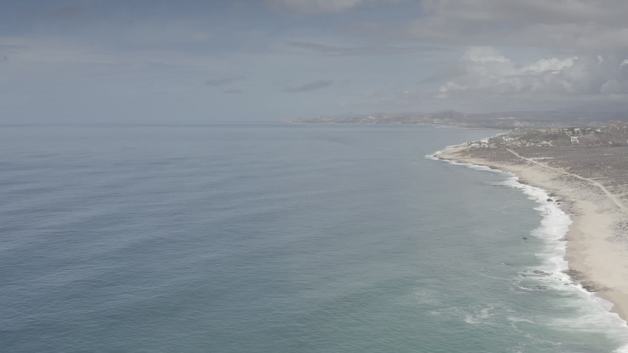 Ocean and beach seen from above with foamy surf.