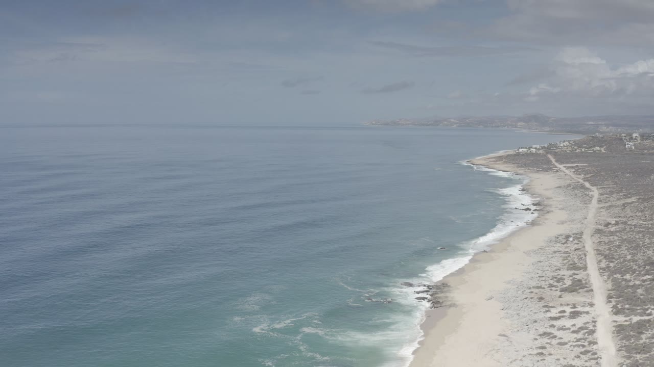 Blue sea beside a sandy beach and scrubby coast
