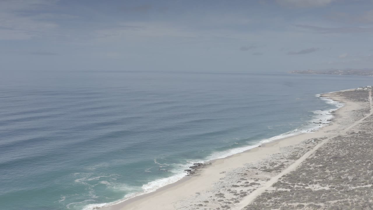 Aerial coastline with blue ocean, pale beach, and scrub land