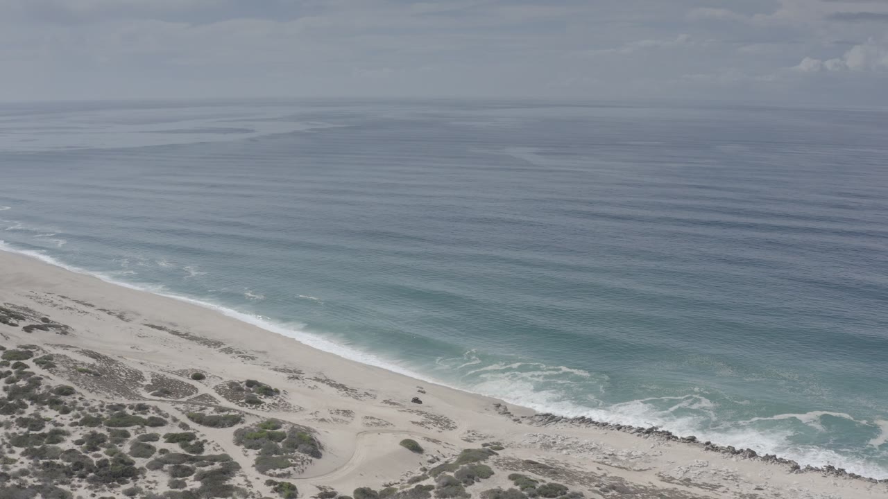 High coastal view with empty beach and rolling waves