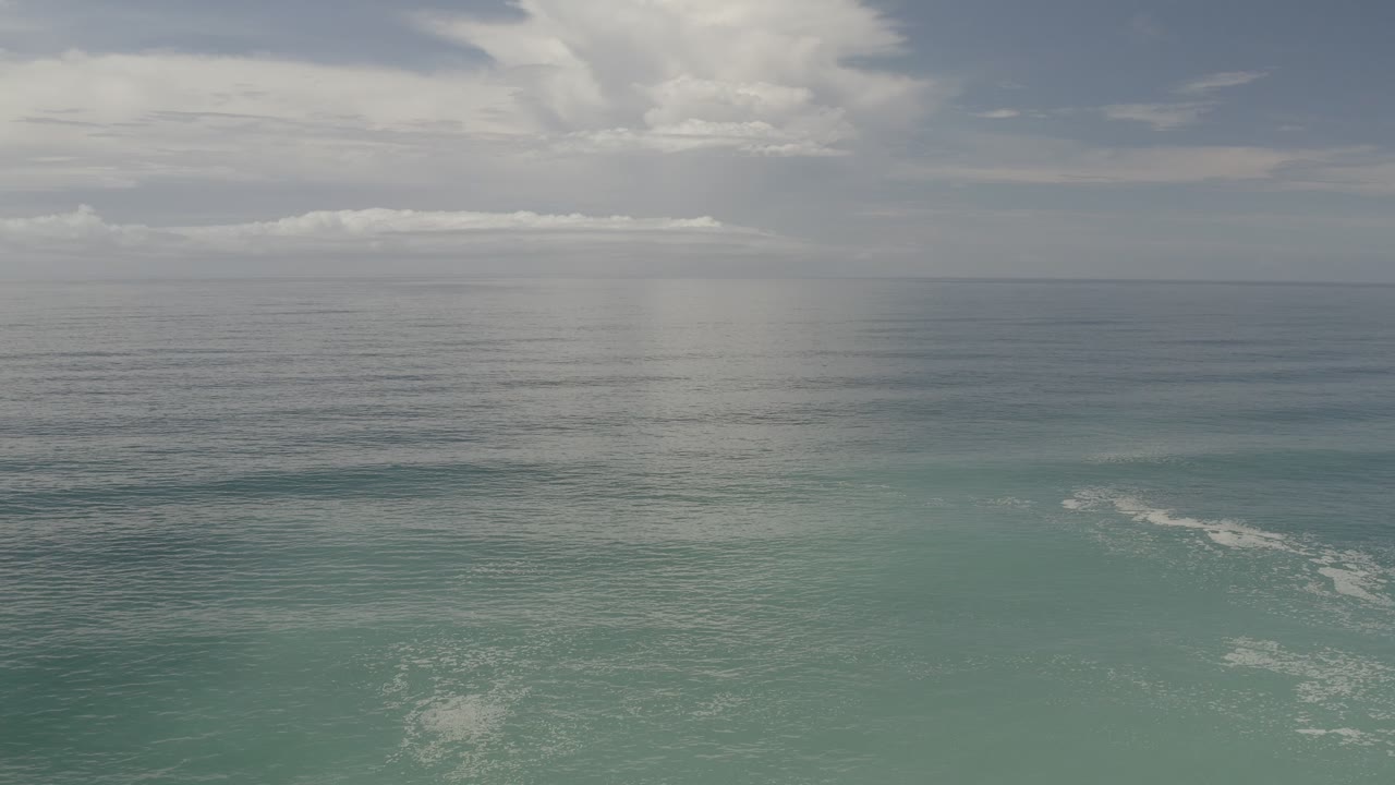 Cloudy ocean scene with a vertical rain shaft over the water.