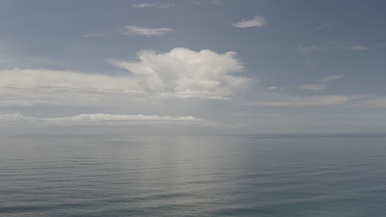Open sea with bright cloud and faint vertical haze