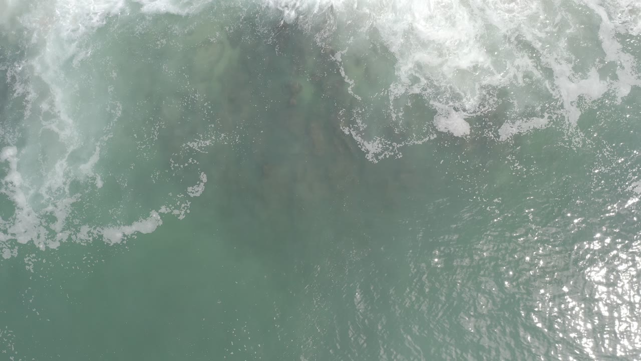 Overhead surf foam breaking across green-blue water.