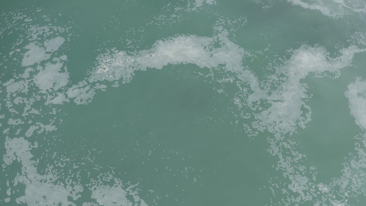 Foamy white wave fragments over muted ocean water